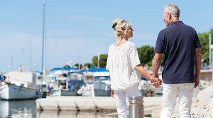 A couple hand in hand walking at the harbour.