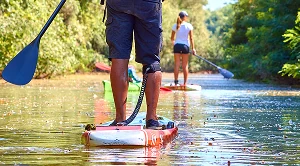 A couple paddleboarding on a river together on a date.