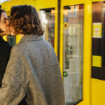 Man and woman kissing in front of arriving train as a symbol for how to get a girlfriend