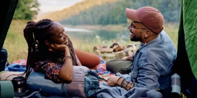 A couple in a tent in nature, talking and eating.