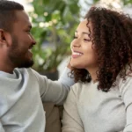 Couple sitting on a couch having a nice conversationg both smiling