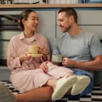 Couple sitting on the kitchenfloor drinking coffee and talking