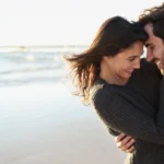 A man and a woman embrace on the beach as a symbol of eharmony