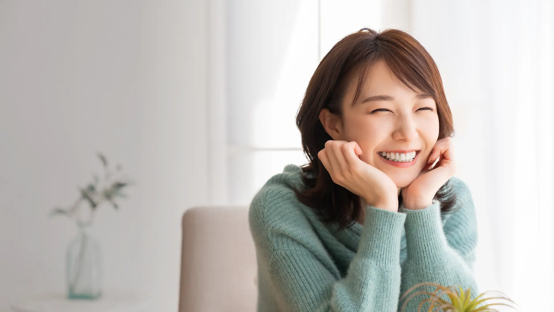Korean Woman sitting at a table and smiling.